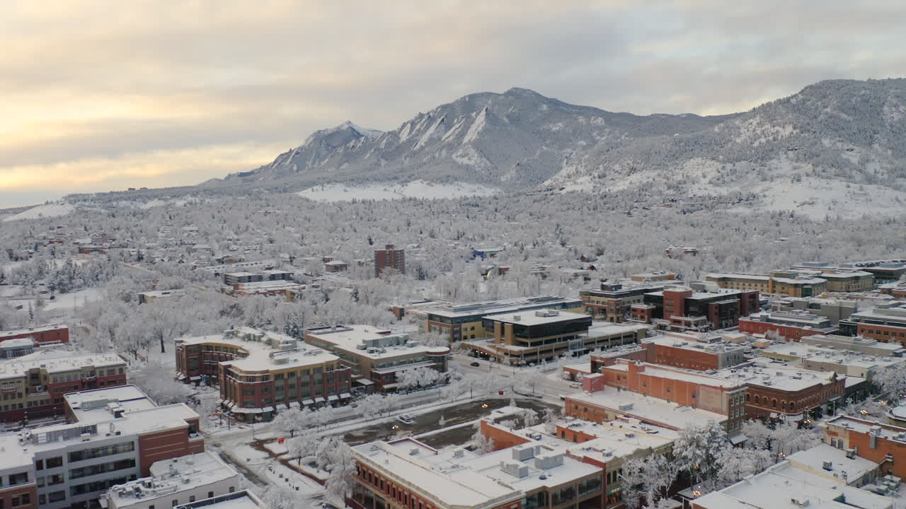 disparo de drones bajos avanzando de boulder colorado, rocky flatiron mountains y pearl street después de una gran tormenta de nieve invernal cubre árboles, casas, calles y vecindarios en nieve blanca fresca