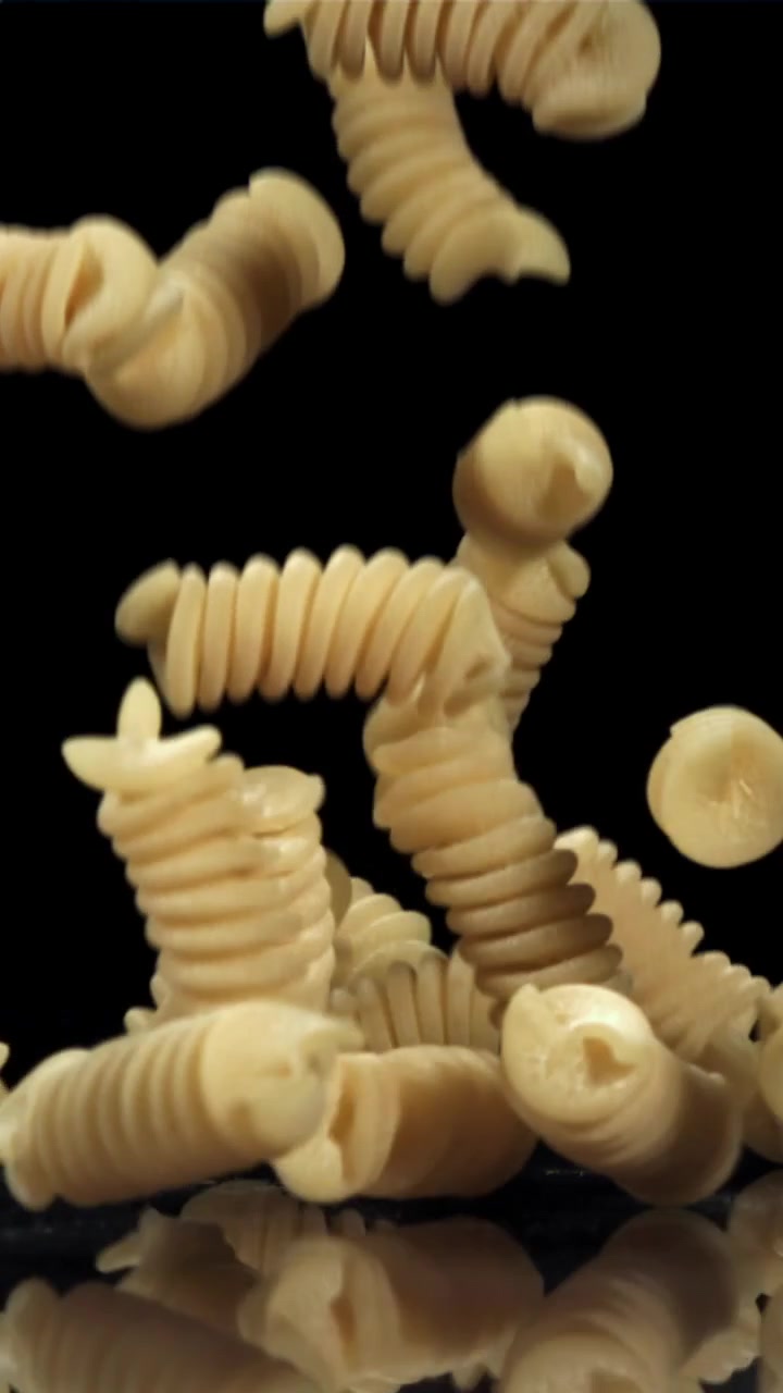 Fusilli secchi che cadono al rallentatore su sfondo nero