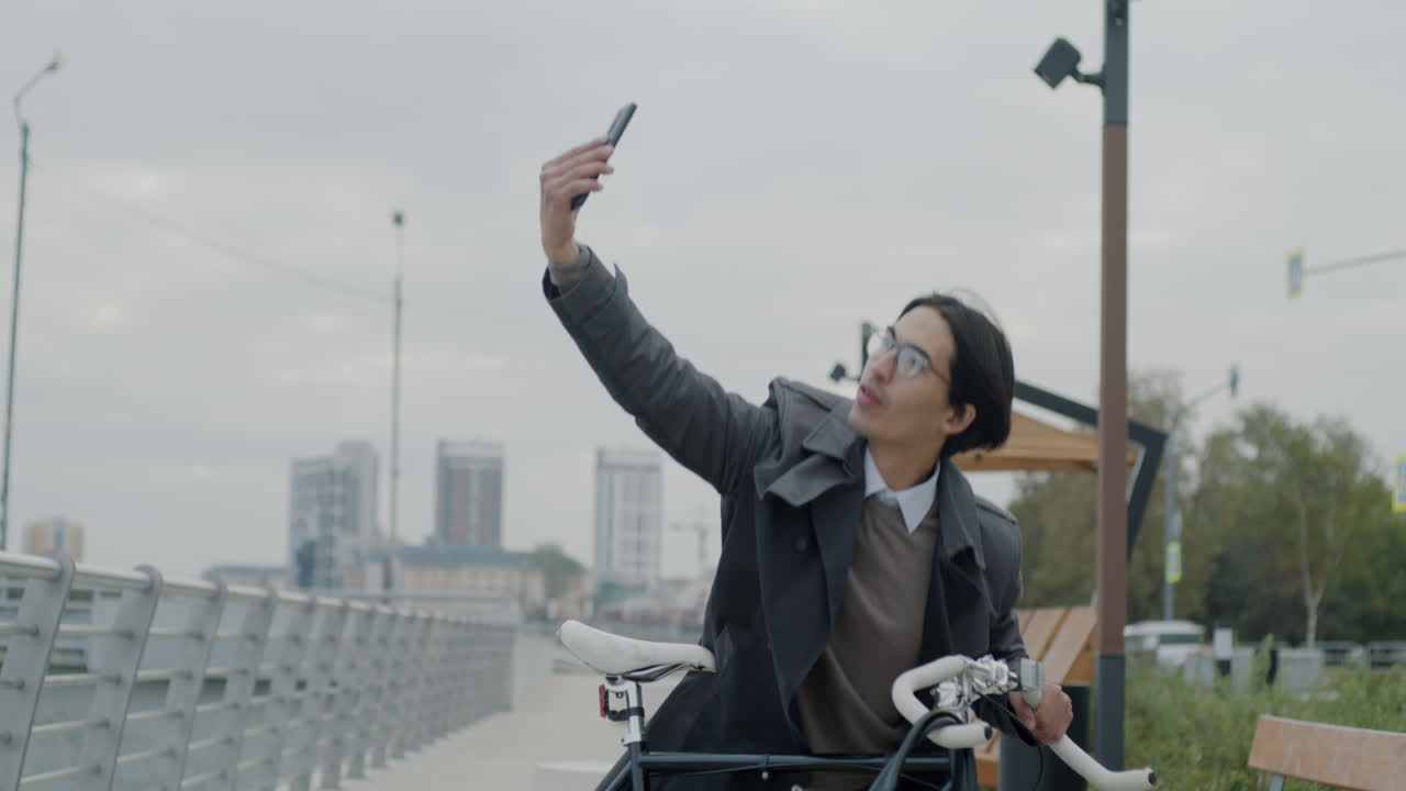 Man taking a selfie while walking his bike in the city