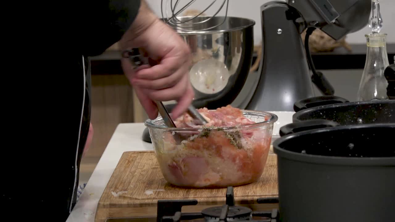 In a busy kitchen, a cook combines various ingredients with ground meat in a large bowl. The process focuses on creating a flavorful mixture for delicious homemade meals