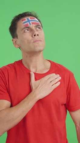 man listening to the norway national anthem with solemnity