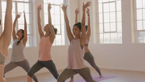 yoga class multi ethnic women practicing warrior pose enjoying healthy lifestyle exercising in fitness studio at sunrise