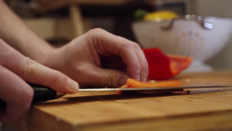 el chef corta pimiento rojo grande en la tabla de cortar, en la cocina