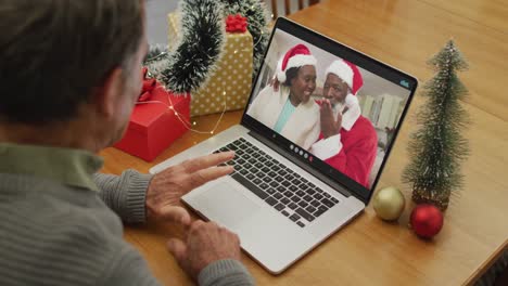 Happy-caucasian-senior-man-on-video-call-with-friends-at-christmas-time