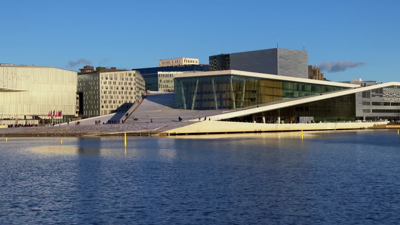Oslo Opera House Norway Norge winter OsloFjord afternoon early sunset arctic sun clear skies tourist attraction people walking breezy sea birds Oslo Library Munch sauna buildings pan left motion