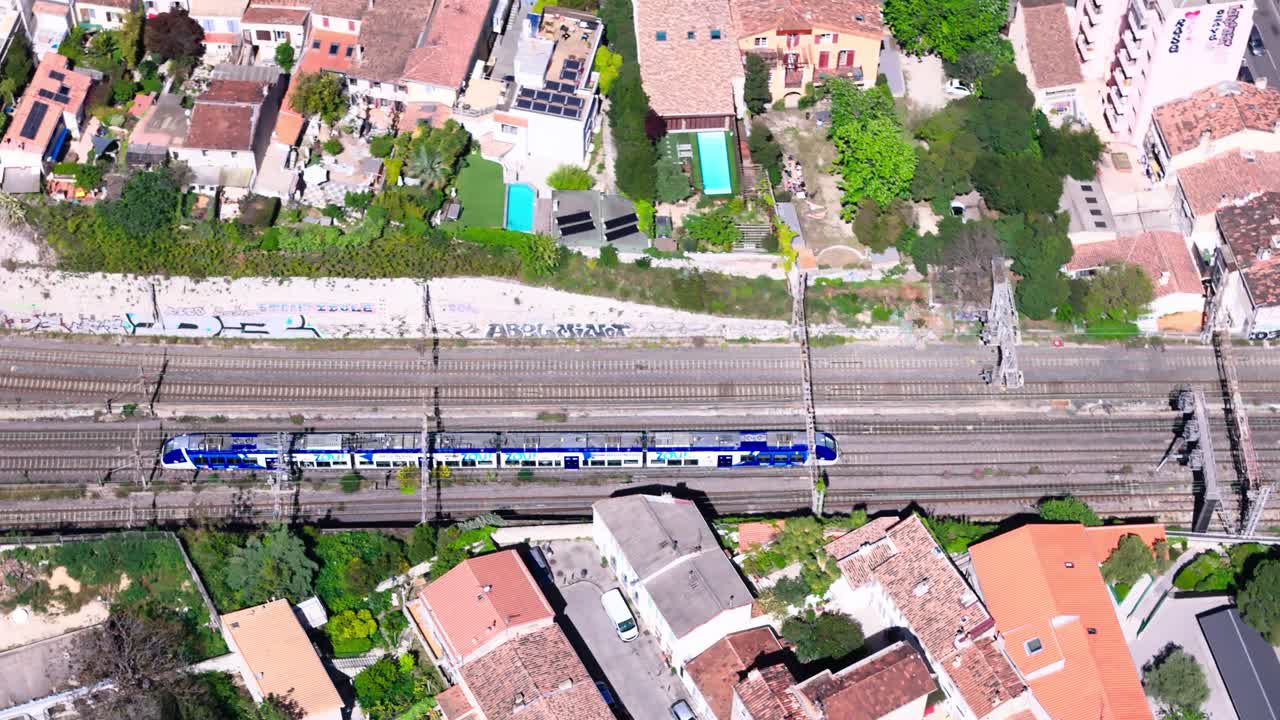 Drone view of blue train entering tunnel at 5 way railway in Marseille, France