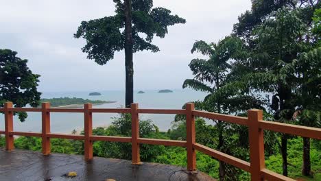 Walking-to-the-fence-on-a-Scenic-View-Point-with-Islands-in-the-Ocean-on-Koh-Chang-Island,-Thailand,-Asia