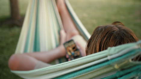 woman relaxing in hammock with phone