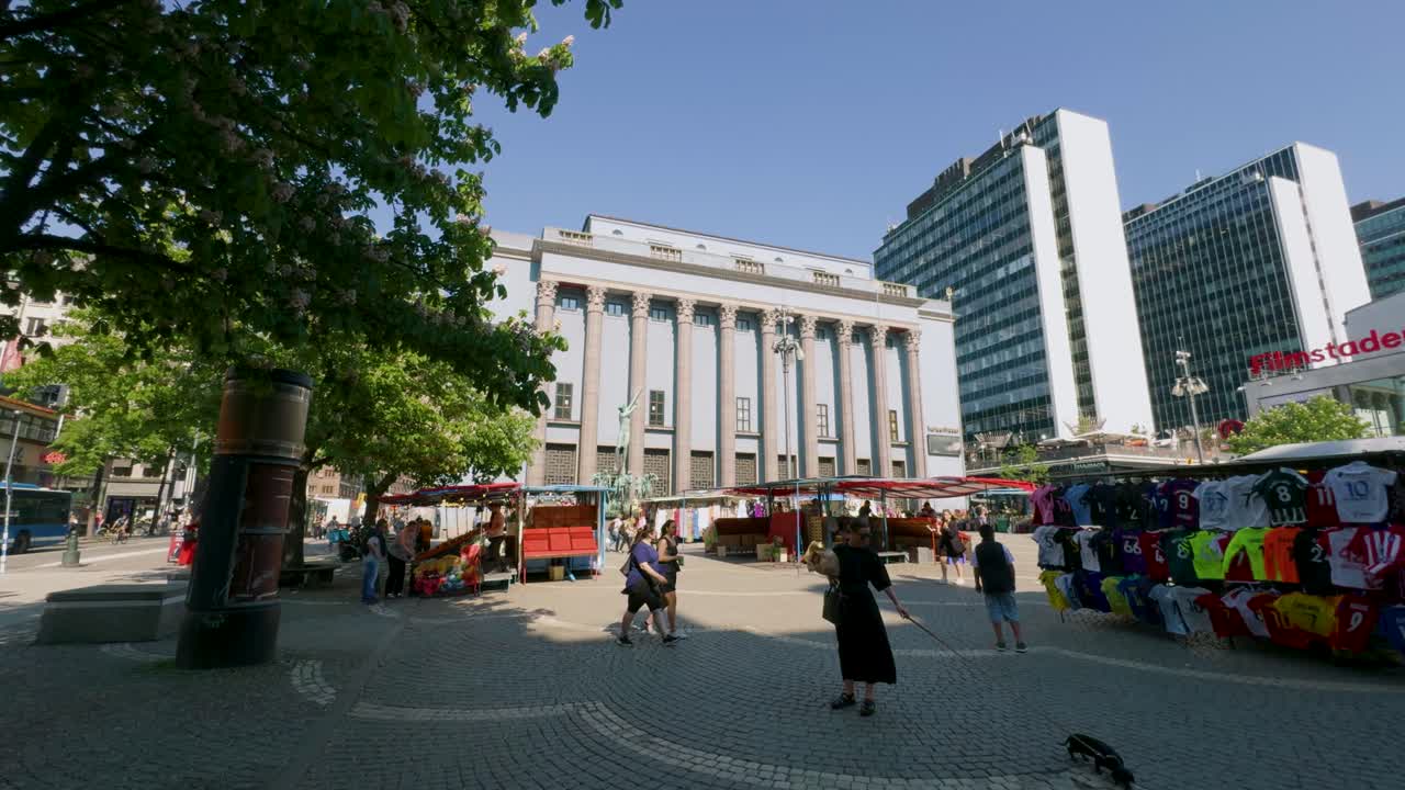 People By Market At Hotorget City Square, Stockholm, Sweden. Concert Hall In Background. wide shot