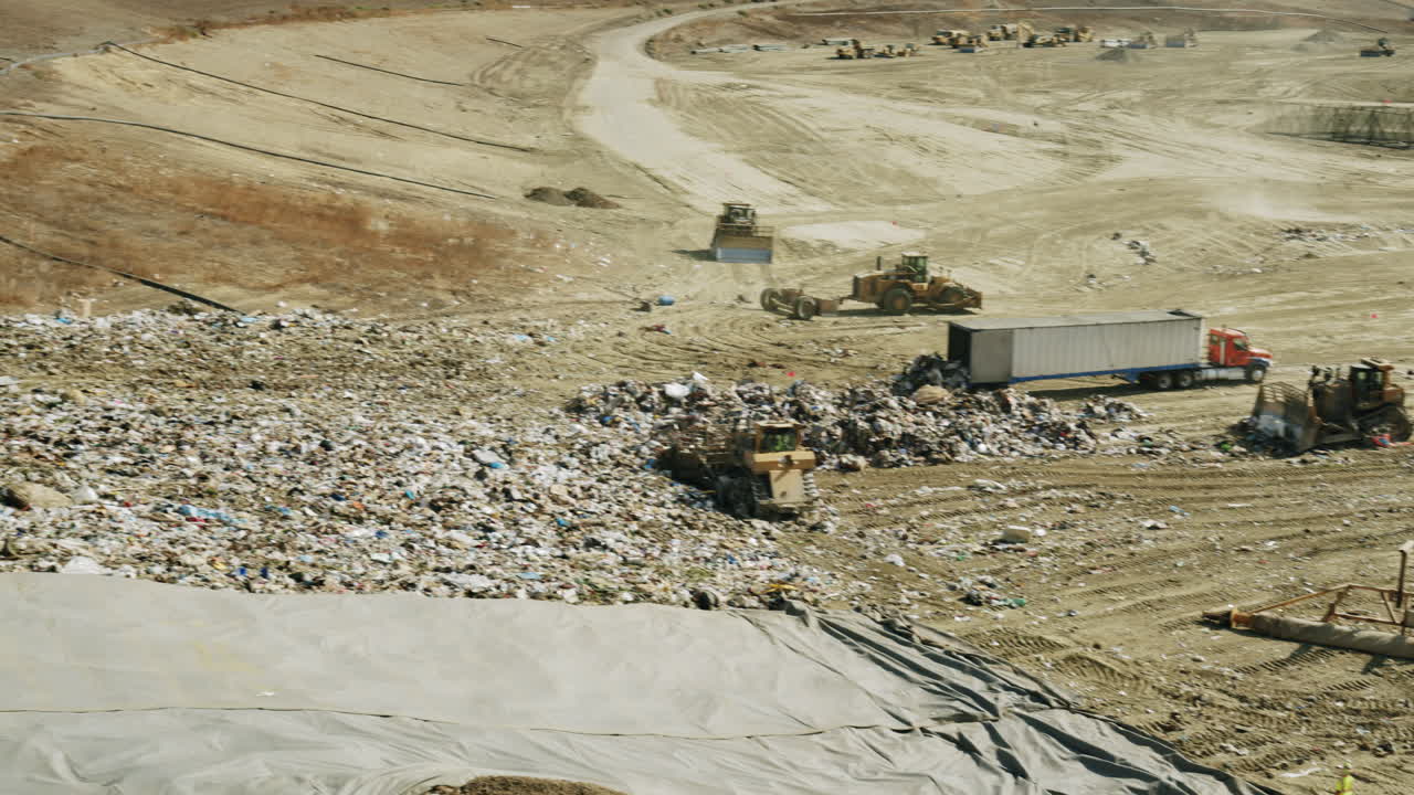Large landfill site with heavy machinery and a semi-trailer truck