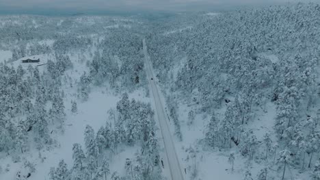 drone footage of an ev driving in beautiful snowy landscape in norway with snow covered tree tops