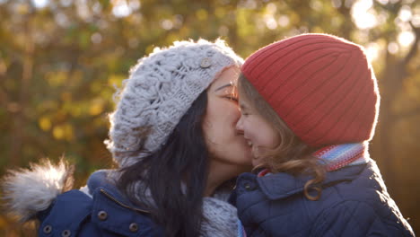 mother cuddling daughter on walk in autumn countryside