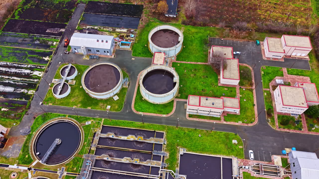 Water treatment facility in operation during the day showing various tanks and buildings for processing water in a rural area