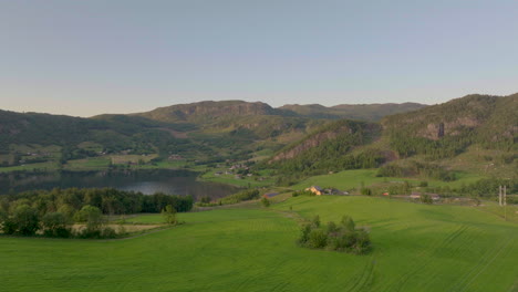 lush, beautiful farm house overlooking mountain lake. aerial