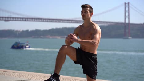 Focused-bare-chested-sportsman-exercising-near-river