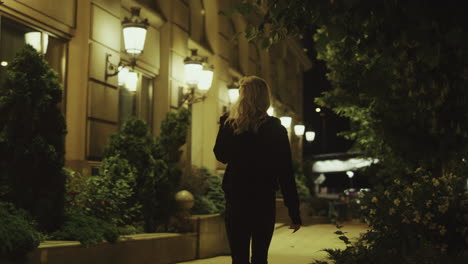 Woman-going-away-street-at-late-night-in-modern-city-outdoors.