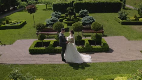 Newlyweds-bride-and-groom-with-bouquet-in-park,-wedding-couple-first-meeting,-aerial-drone-view