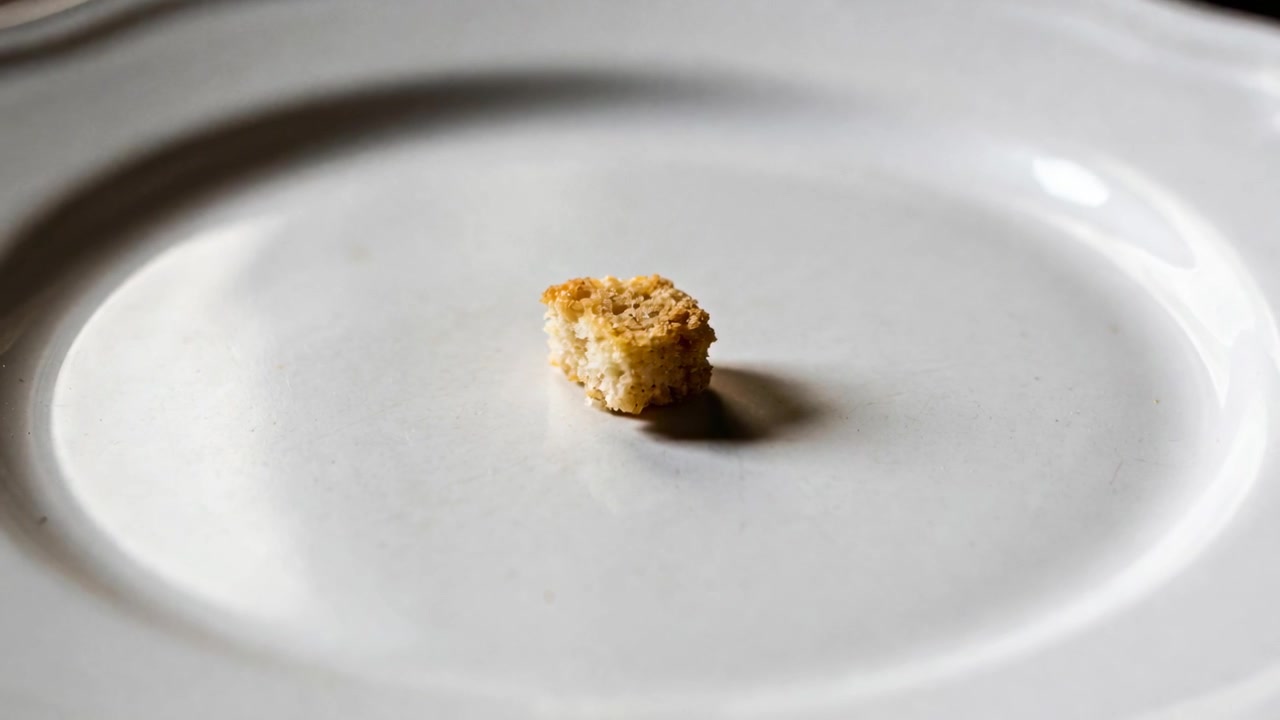 Pulling focus, camera highlighting crumb on white plate at kitchen table, revealing texture