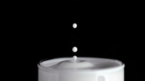 a drop falling in super slow motion into a milk glass