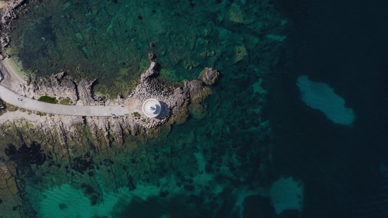 Top down drone footage of Saint Theodore - Fanari Lighthouse near Argostoli, Kefalonia. A striking circular structure surrounded by turquoise waters