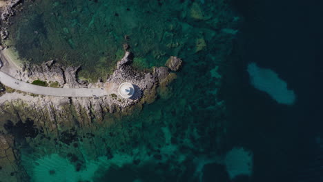 top down drone footage of saint theodore - fanari lighthouse near argostoli, kefalonia. a striking circular structure surrounded by turquoise waters