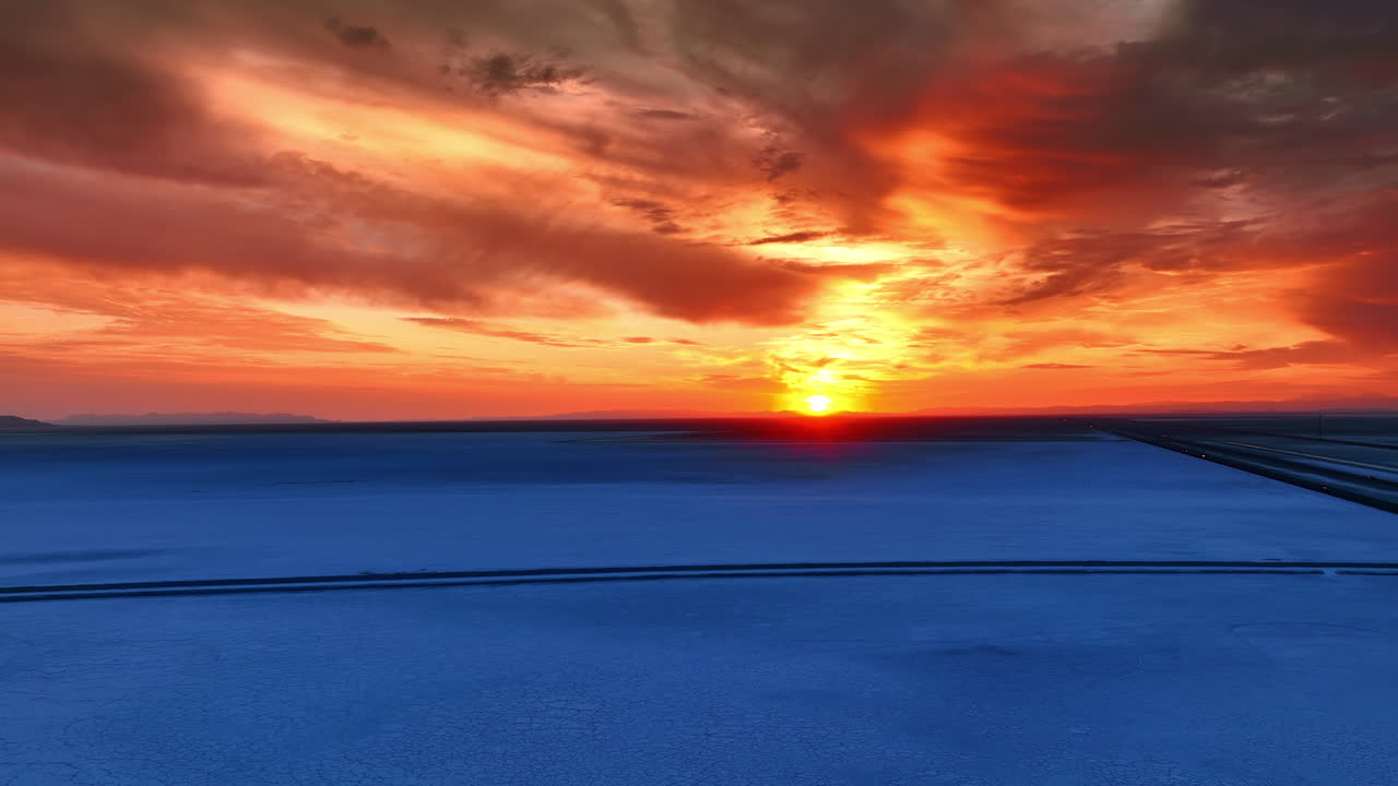 Enormous salty plain colored blue at sunset time. Amazing cloudy sky colored orange by the setting sun