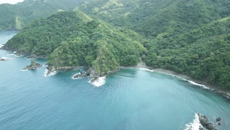 Amazing-aerial-of-a-coastal-black-sand-beach-with-mountains-as-the-backdrop-on-the-Caribbean-island-of-Tobago