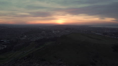 static shot of edinburgh cityscape from the mountain moments after sunset from arthurs seat with wonderful sunset, blue hour light with cars passing by down below