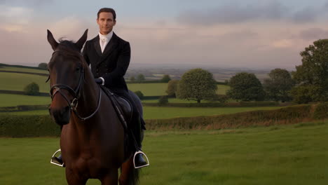 a man in formal riding attire on a horse in a green countryside landscape