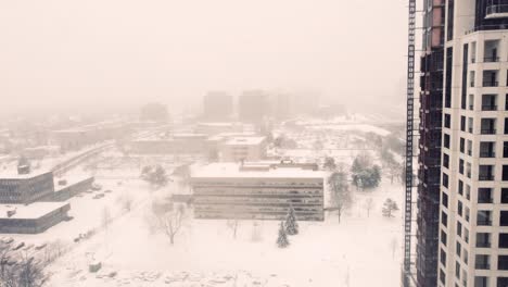 Aerial-Flying-In-Between-Apartment-Buildings-During-Snow-Blizzard-With-Reveal-Of-Highway-In-Toronto,-Canada