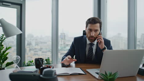 Gerente-Llamando-A-Los-Clientes-Con-Teléfonos-Inteligentes-Tomando-Notas-En-Un-Cuaderno-En-La-Mesa-De-Cerca.