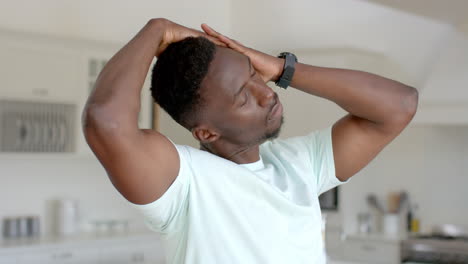 Focused-african-american-man-stretching-in-sunny-living-room,-slow-motion