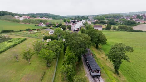 Small-steam-train-carrying-tourists,-leaving-the-station-in-reverse-in-the-village-of-Martel-in-summer,-Lot,-France