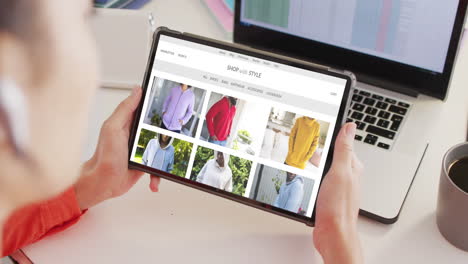 caucasian woman at desk using tablet, shopping online for clothes, slow motion