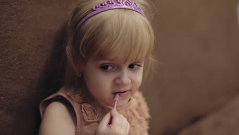 niña feliz de tres años. niña rubia linda. ojos marrones. niña se hace el maquillaje