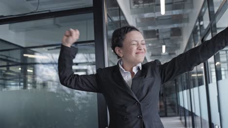 happy woman in business suit dancing in office slow-mo, celebrating success