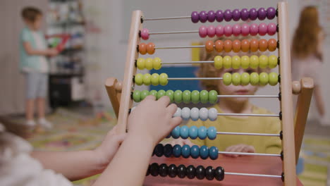 camera focuses on the hands of little kid playing with a panel moving wooden pieces