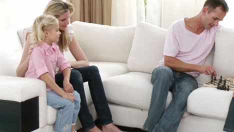 Father-and-son-playing-chess-on-the-sofa-with-mother-and-sister