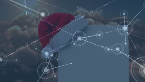 Animation-of-network-of-connections-with-santa-hat-and-card-with-copy-space-over-clouds