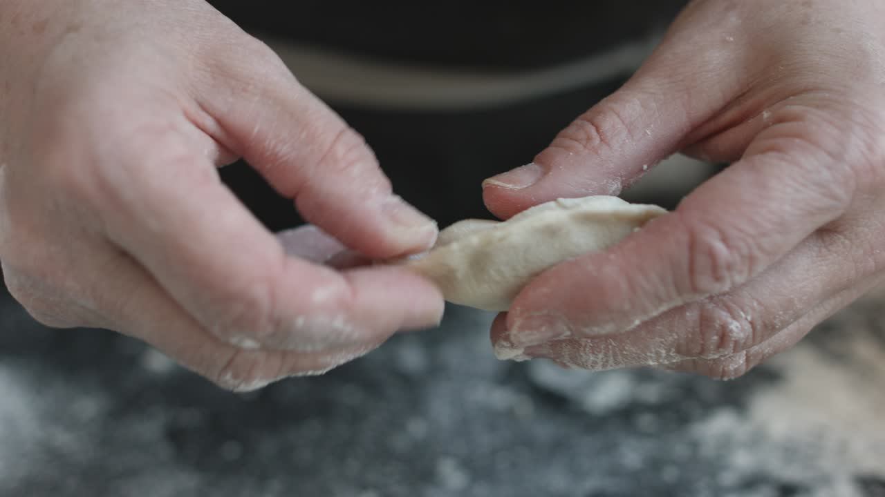 Two hands making meat dumplings.