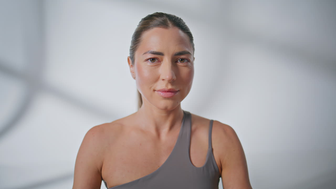 Portrait yoga girl looking camera meditating posing at white wall background