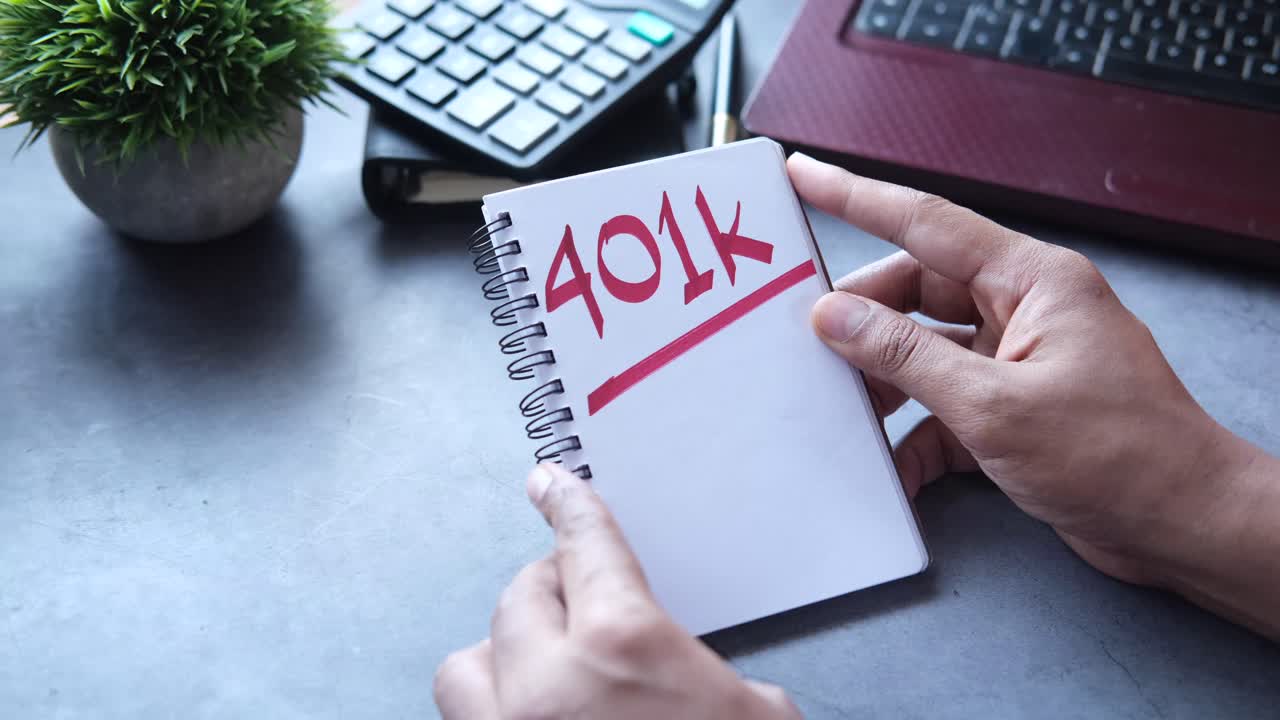 401k가 적혀있는 노트북을 들고 있는 사람