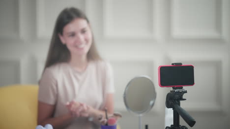 woman recording makeup tutorial on smartphone