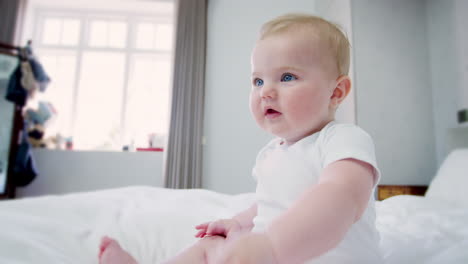 happy baby boy sitting on parents bed