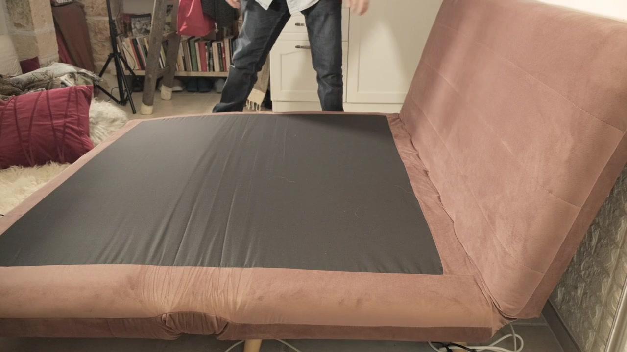 Um homem em casa, abrindo e fechando um sofá pequeno, elegante, dobrável e confortável