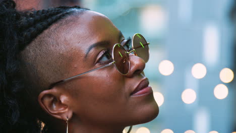 Moda-Joven-Mujer-Negra-Con-Gafas-De-Sol,-Disparo-A-La-Cabeza,-Vista-Lateral,-Luces-Bokeh-En-Segundo-Plano.