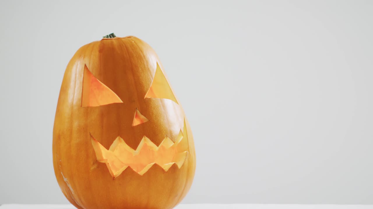 vista de cerca de la cara aterradora tallada calabaza de halloween contra un fondo gris