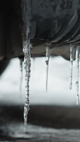 close-up of icy stalactites hanging from a car's mudguard, showcasing frozen textures and the effect of subzero temperatures on vehicle exteriors