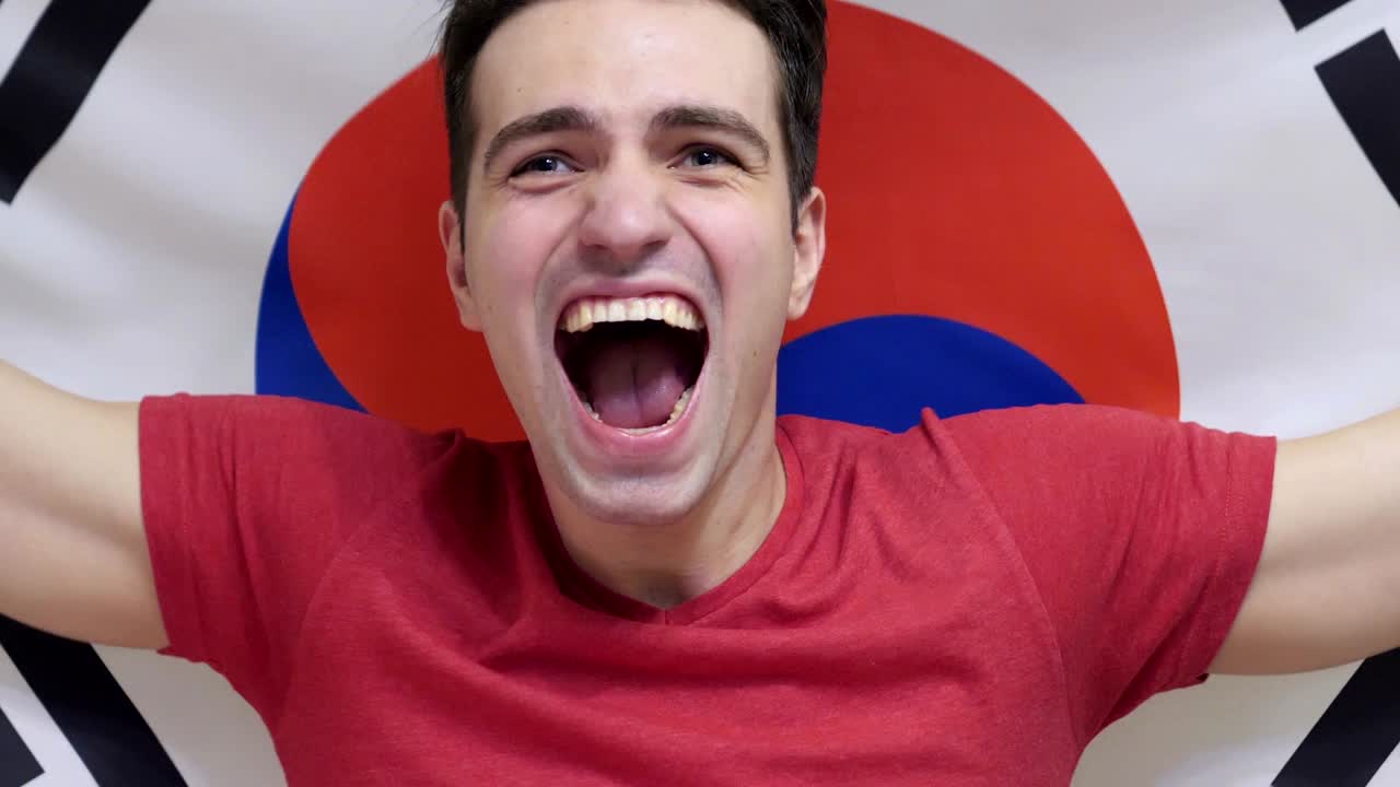 un joven surcoreano celebra sosteniendo la bandera de corea del sur en cámara lenta