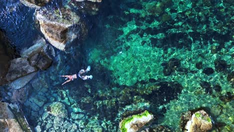 male tourist swimming in the transparent waters of a bay in ibiza, spain. nice aerial view flight vertical bird's eye view drone